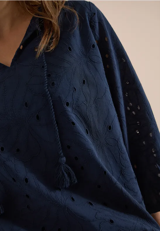 Nahaufnahme einer dunkelblauen Bluse mit Lochstickerei, V-Ausschnitt und Quasten