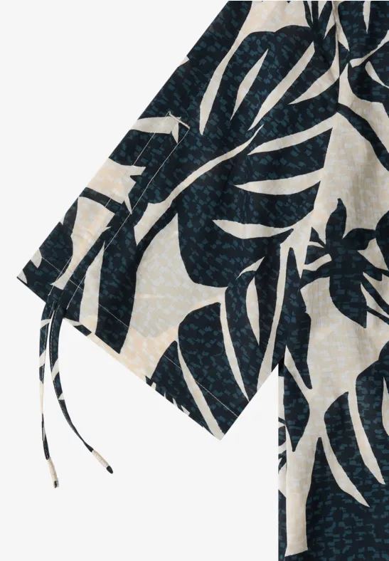 Weiße Stoffjacke mit dunkelblauem Monstera-Blattmuster und Kimonoschnitt.