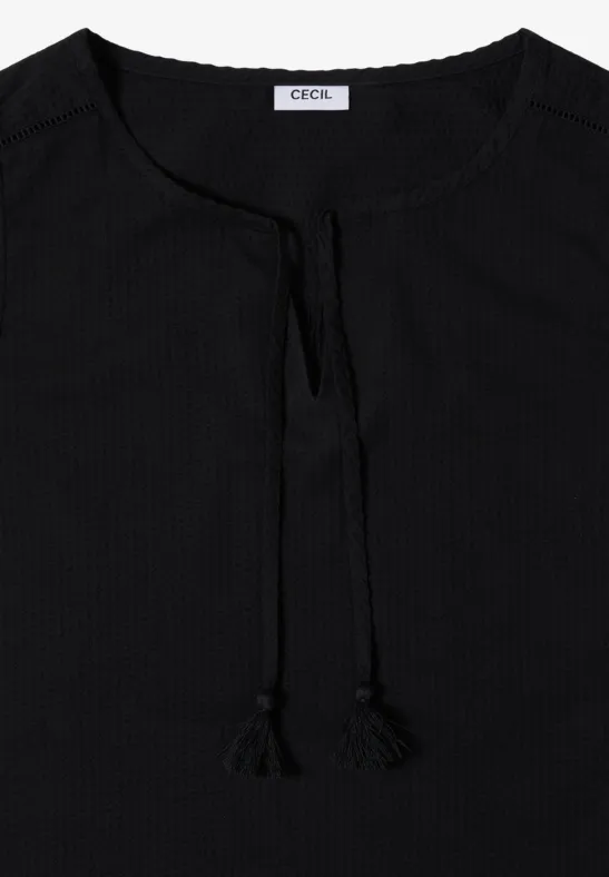 Blouse noire à encolure ronde, fente centrale et liens décoratifs à l'avant.