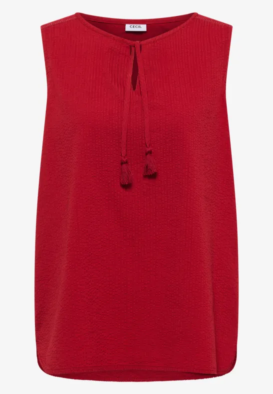 Top rouge sans manches texturé avec cordons à nouer et pompons.