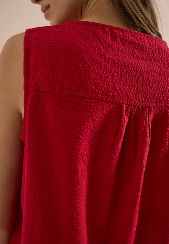 Vue arrière d'une femme portant un top sans manches texturé rouge.