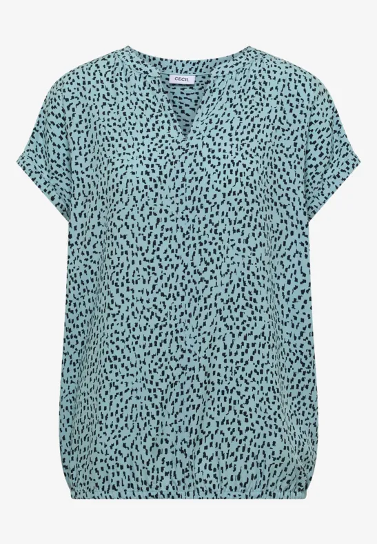 Blouse légère turquoise à pois noirs, col V et manches courtes.