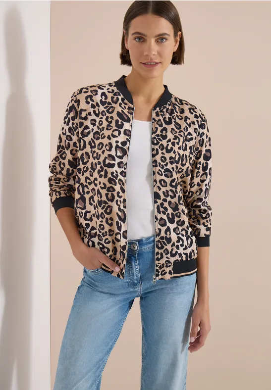 Frau trägt eine Leopardenmuster-Blousonjacke, weiße Bluse und Jeans.