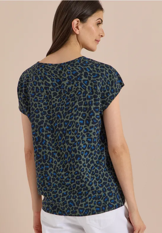 Femme de dos portant un haut à manches courtes avec imprimé léopard bleu et noir.