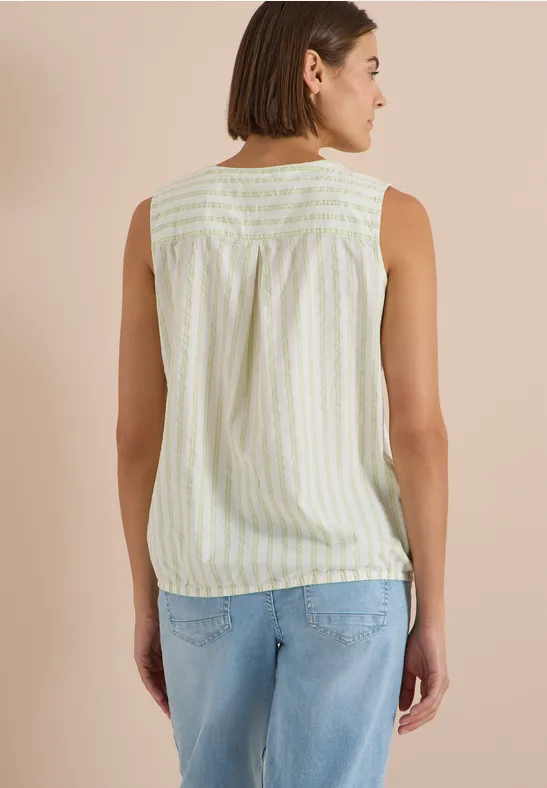 Femme vue de dos portant un haut sans manches à rayures pastel et un jean bleu.