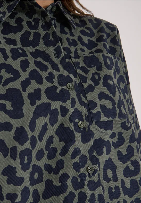 Gros plan d’une chemise vert olive à motifs léopard noirs avec patte de boutonnage.