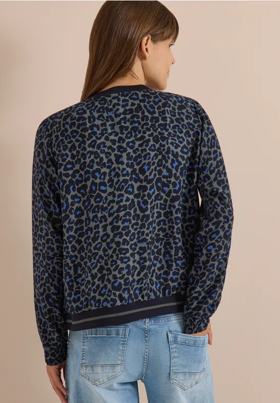 Frau von hinten in blau-schwarz gemustertem Leo-Pullover und hellblauen Jeans.
