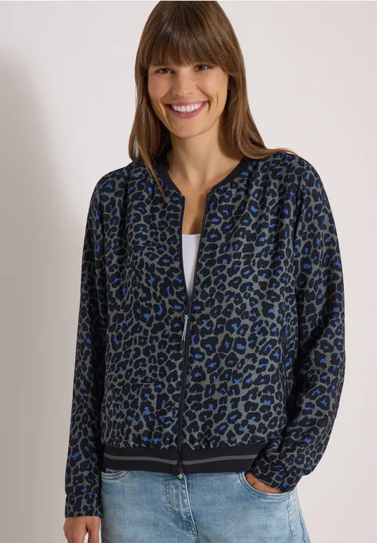 Frau trägt blaue Leo-Jacke, weißes Shirt und Jeans und lächelt.