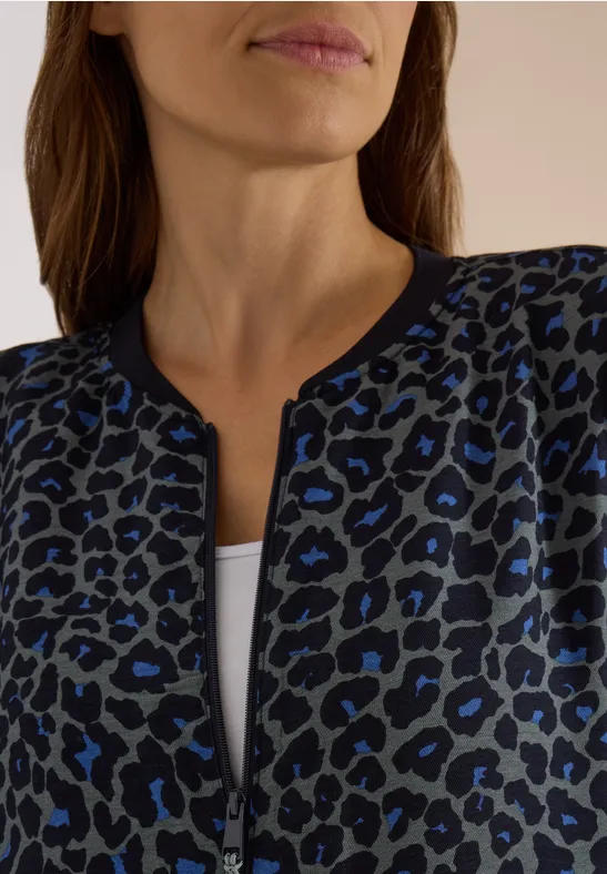 Damenjacke mit blau-schwarzem Leopardenmuster, Reißverschluss, weißes Unterziehshirt, Nahaufnahme.