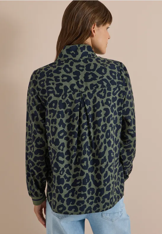 Femme de dos en chemise bleu-vert à motif léopard noir et jean