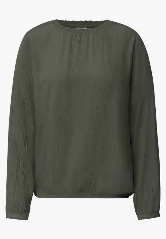 Blouse unie vert olive à manches longues et encolure ronde.