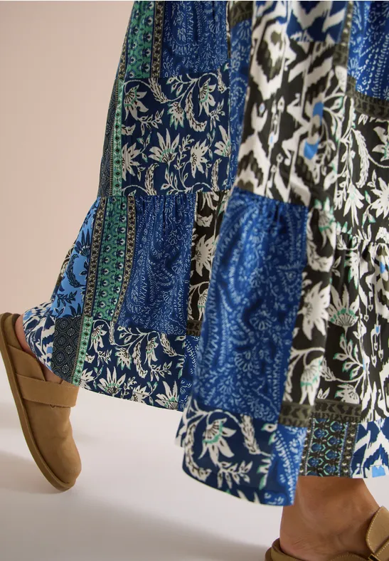 Eine lange Patchwork-Rock mit blauen floralen und geometrischen Mustern, kombiniert mit schlammfarbener Slipper.