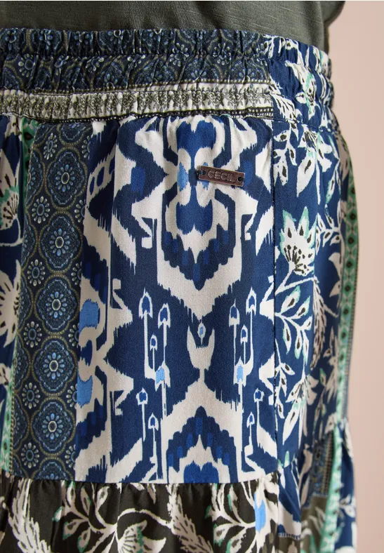 Nahaufnahme eines blauen, gemusterten Stoffes mit weiß-grünen Ornamenten und Gummibund.