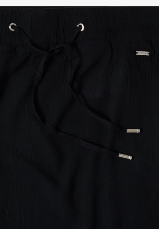 Pantalon noir en tissu avec cordon et embouts métalliques.
