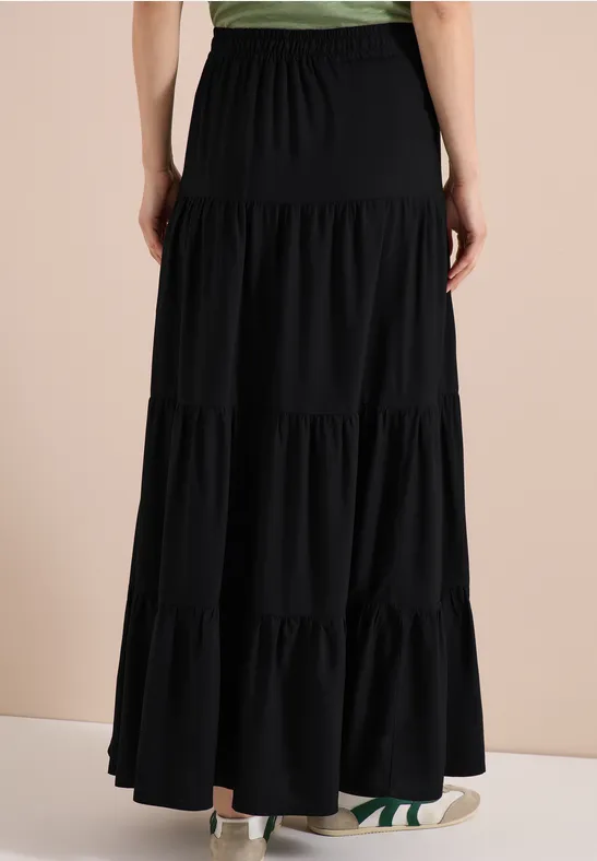Vue de dos d'une longue jupe noire à volants et taille élastique.