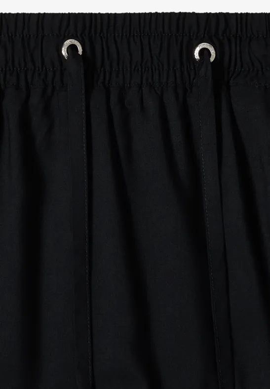 Tissu noir avec taille élastique et cordon, coutures simples en haut.