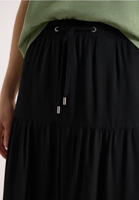 Jupe noire à volants échelonnés, taille élastique nouée, vue d’une blouse verte