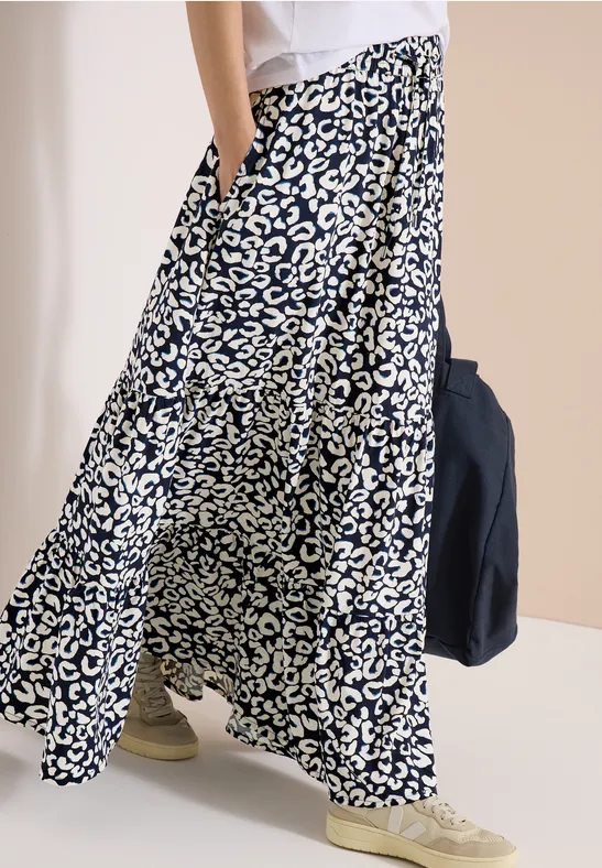 Weite Hose mit schwarz-weiß abstraktem Muster, seitlicher Tasche, kombiniert mit hellen Sneakers.