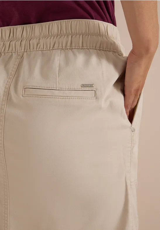 Pantalon beige à taille élastiquée, poche passepoilée au dos et poche prise latérale.