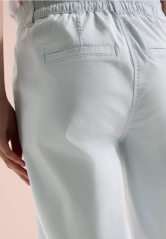 Person von hinten in hellblauen, elastischen Hosen mit Gesäßtasche.