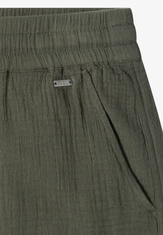 Nahaufnahme einer dunkelgrünen, strukturierten Hose mit elastischem Bund und Seitentasche.