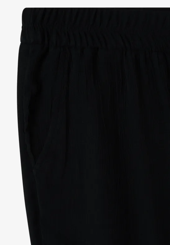 Schwarze, lockere Hose mit elastischem Bund und seitlicher Tasche.