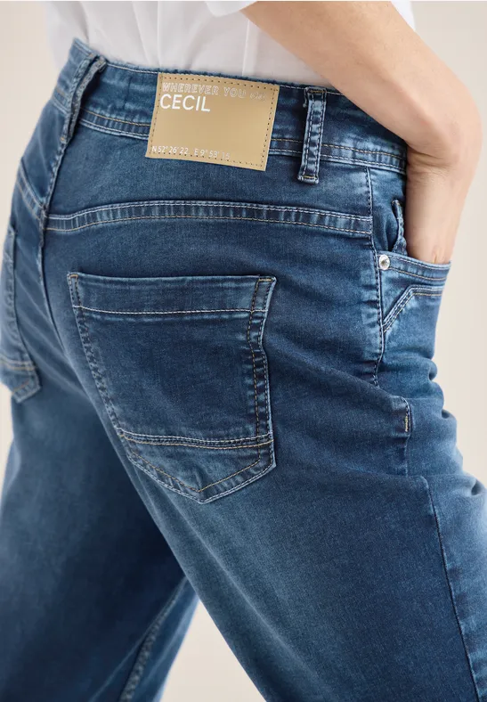 Vue arrière d'une personne en jean bleu CECIL avec étiquette beige au-dessus de la poche arrière.