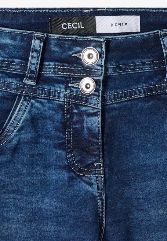 Gros plan d’un jean bleu à double boutonnière, poche oblique et étiquette 'CECIL'.