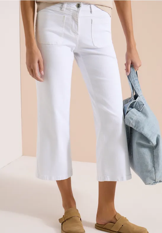 Jean blanc court évasé porté avec sandales et sac en denim.