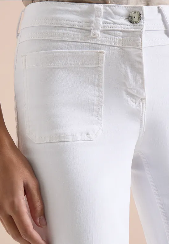 Gros plan d'un jean blanc ajusté avec poche avant et main posée sur la cuisse.