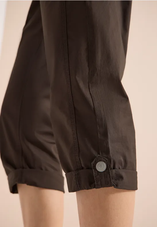 Braune, locker sitzende Hosenbeine mit seitlichem Knopfdetail und gerafften, gekrempelten Bündchen.