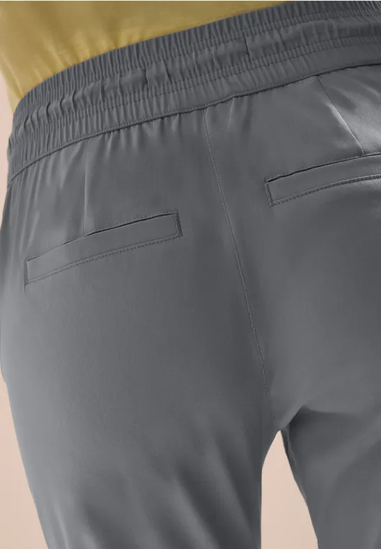 Rückansicht einer grauen Sporthose mit Gummibund und zwei Gesäßtaschen vor hellem Hintergrund.
