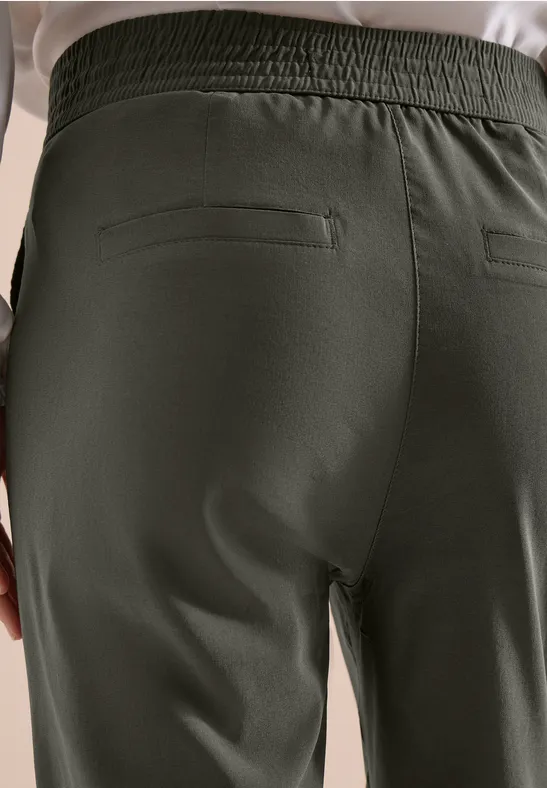 Rückansicht dunkelgrüner Hosen mit elastischem Bund und verschließbarer Rückentasche.