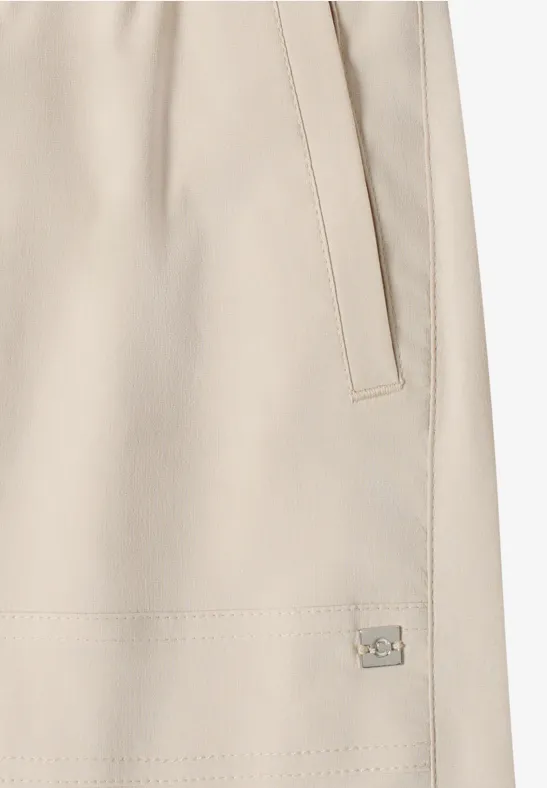 Beige Jacke mit seitlicher Eingrifftasche, sichtbarer Naht und kleinem Metalllabel.