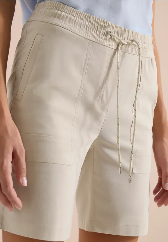 Cremefarbene Bermudashorts mit elastischem Bund und Kordelzug, kombiniert mit einem hellblauen Top.