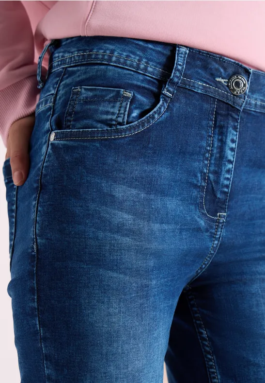 Nahe Aufnahme einer Person in blauen Jeans und rosa Oberteil, Hand in Tasche.