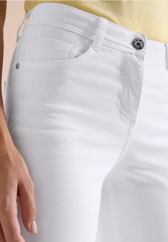 Hüftansicht einer weißen Jeanshose an einer Person mit Hand am Oberschenkel.