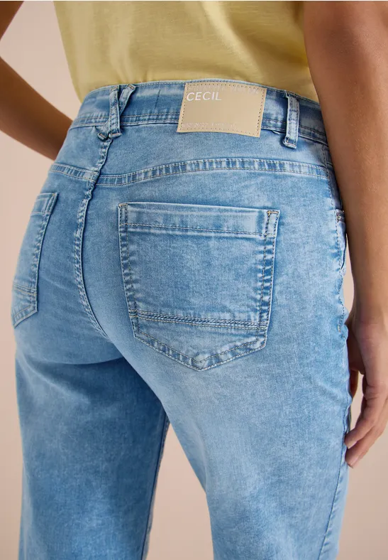 Rückansicht einer Person in hellblauen Jeans und gelbem Oberteil.