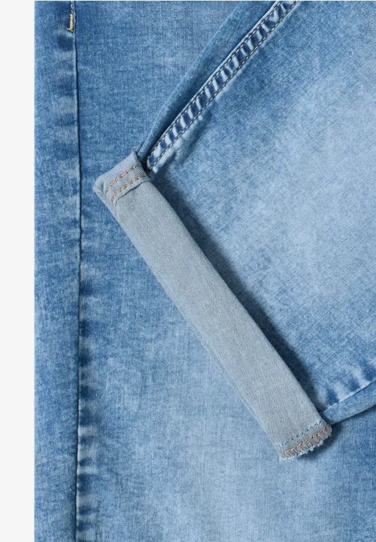 Nahaufnahme einer blauen Jeanshose: sichtbare Tasche, Gürtelschlaufen und robuste Nahtdetails.