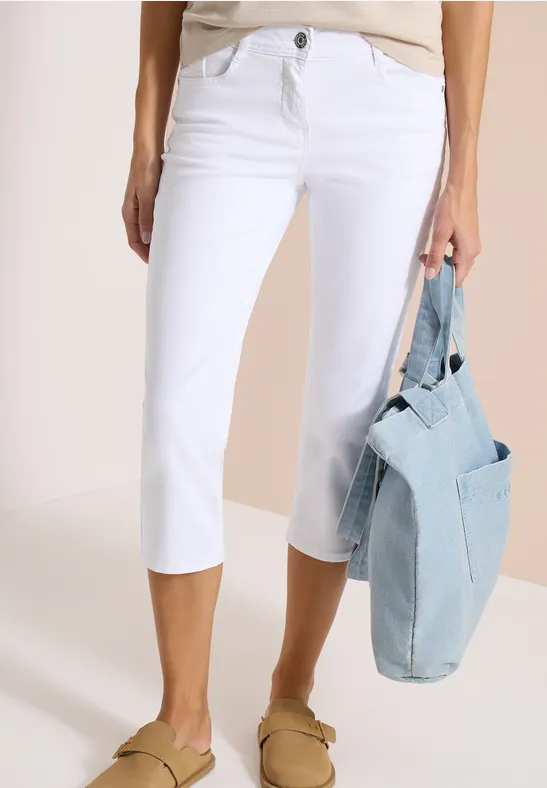 Weißer Caprihose-Modell mit hellem Denim-Tasche und beigen Loafers, lässiger Sommer-Look.