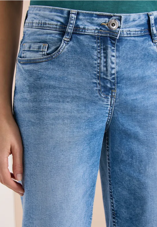 Nahaufnahme einer Person in hellblauen Jeans mit sichtbarer Nahttasche und Hand an der Seite.