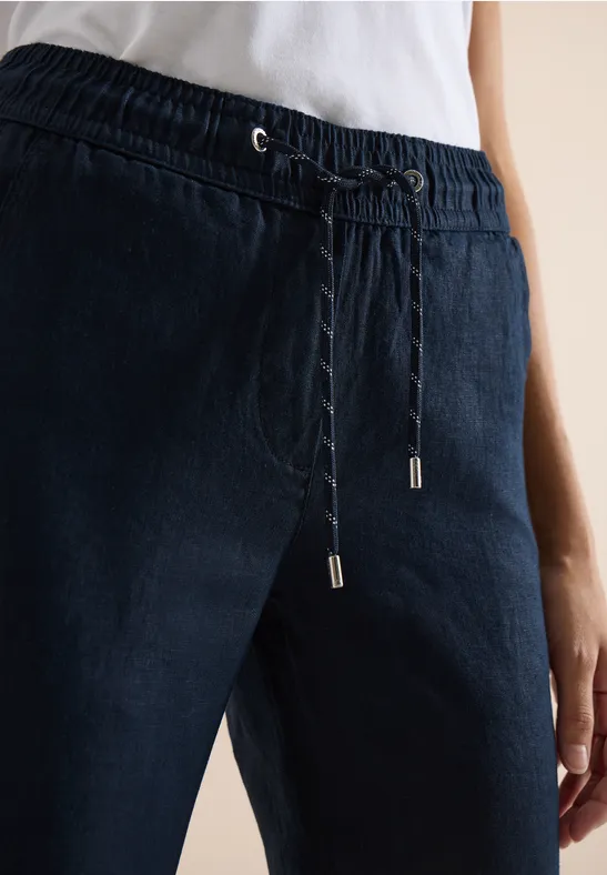 Eine Person trägt eine dunkelblaue Hose mit elastischem Bund und Kordelzug.