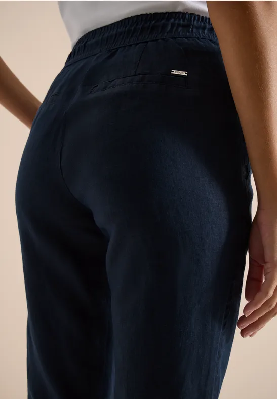 Rückenansicht einer Person in dunkelblauer Hose mit elastischem Bund und feiner Struktur.