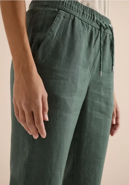 Pantalon en lin vert foncé avec taille élastique et cordon, porté par une personne