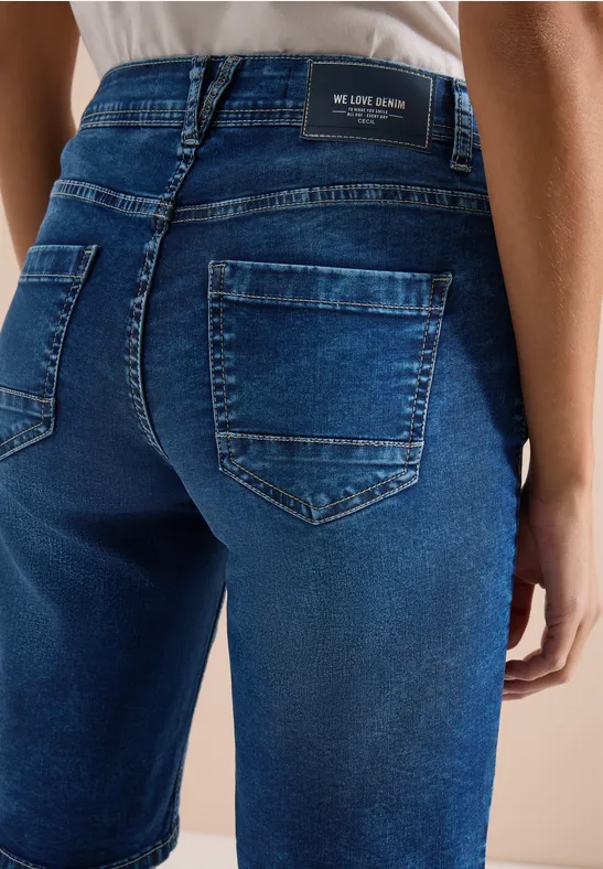 Nahaufnahme einer Person in dunkelblauen Jeans von hinten mit sichtbaren Gesäßtaschen.