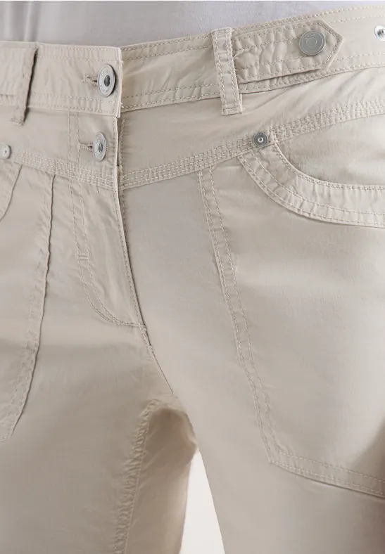 Hellbeige Hose mit Gürtelschlaufen, Taschen und silbernen Nieten am Bund.