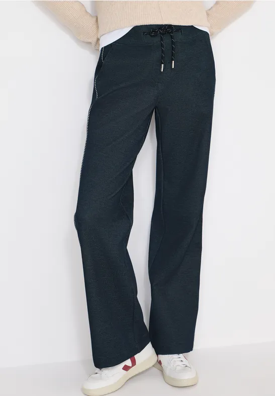 Dunkelblaue, weite Freizeithose mit Kordelzug, kombiniert mit weißen Sneakern.