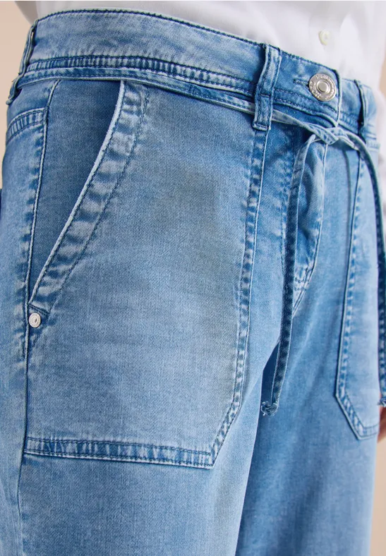 Nahaufnahme einer hellblauen Jeans mit seitlichen Eingrifftaschen und Tunnelzugbund.
