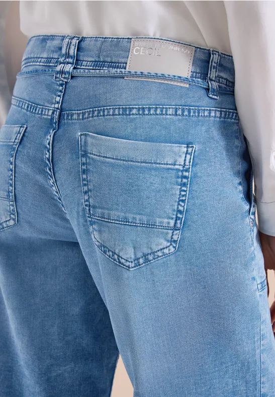 Blick auf das Gesäß einer Person in hellblauen Jeans mit zwei aufgesetzten Taschen und weißem Bundetikett.