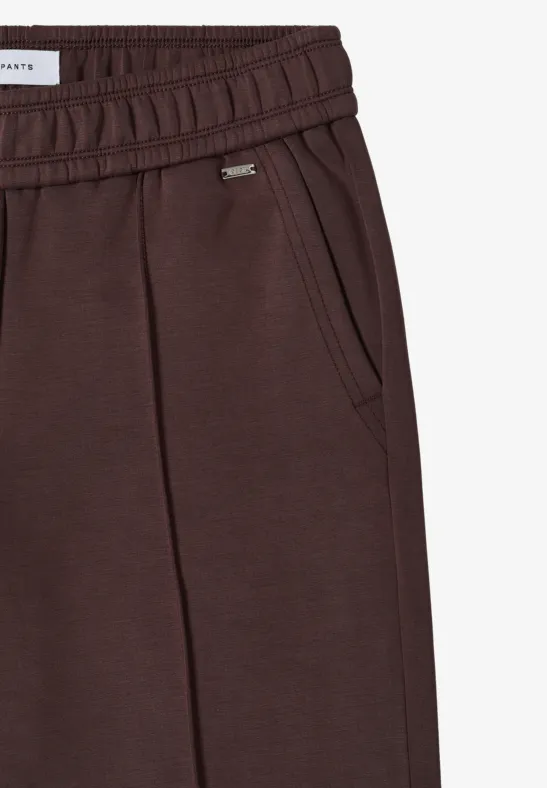 Dunkelbraune Jogginghose mit elastischem Bund, seitlichen Taschen und kleinem Metalllogo.